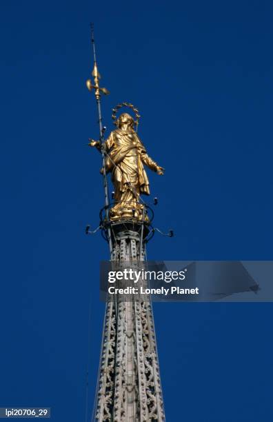 gilded copper statue of madonnina atop duomo's central spire, milan, italy - la madonnina fotografías e imágenes de stock