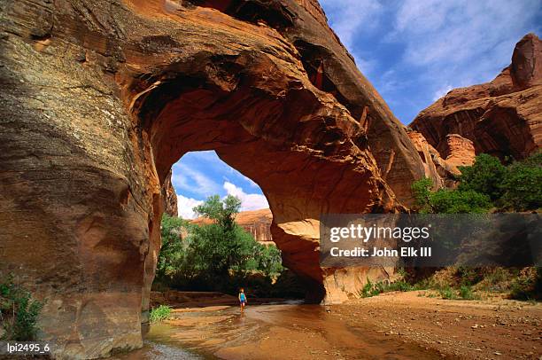 hiker underneath coyote natural bridge, coyote gulch hike, glen canyon national recreation area, united states of america - glen canyon stock pictures, royalty-free photos & images