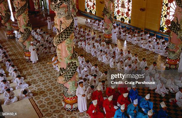 priests and other worshipers praying in caodai great temple, tay ninh, vietnam - tay ninh province stock pictures, royalty-free photos & images