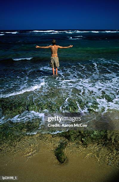 boy walking into the water at playa el luquillo, luquillo, puerto rico - mccoy stock pictures, royalty-free photos & images