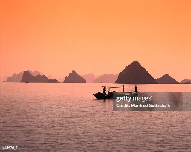 boat on bay waters with islets in background, halong bay, vietnam - halong bay stock pictures, royalty-free photos & images