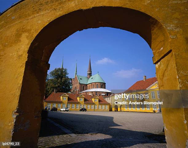 roskilde cathedral framed in archway from the palace garden, roskilde, denmark, europe - kathedraal van roskilde stockfoto's en -beelden