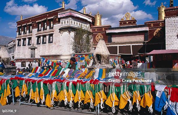 woman selling colourful prayer flags in barkhor square, in front of jokhang temple, lhasa, china - tibet autonomous region stock pictures, royalty-free photos & images
