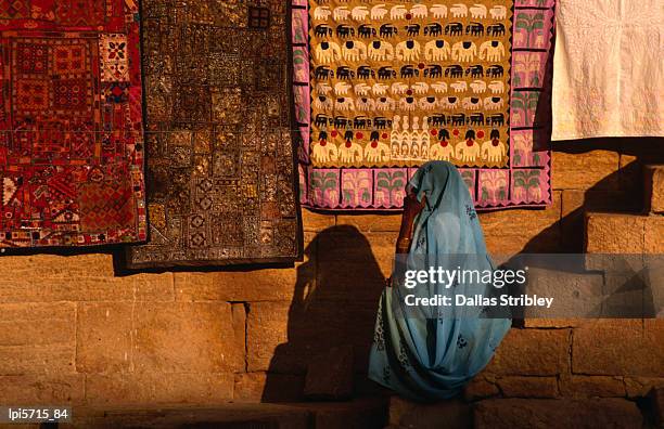 woman in sari sitting in front of rugs for sale. - for sale korte frase stockfoto's en -beelden