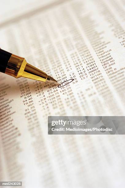 newspaper opened to the financial page with pen circling one figure, extreme close-up - share prices of consumer companies pushes dow jones industrials average sharply higher stockfoto's en -beelden