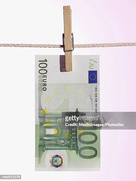close-up of a euro bank note hanging on a clothes line - one hundred euro note stock pictures, royalty-free photos & images