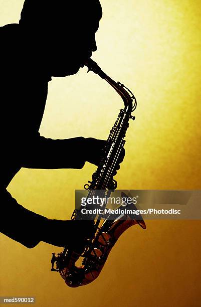 silhouette of man playing a saxophone - bläser stock-fotos und bilder
