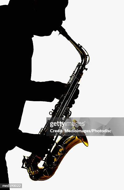 silhouette of man playing a saxophone - bläser stock-fotos und bilder