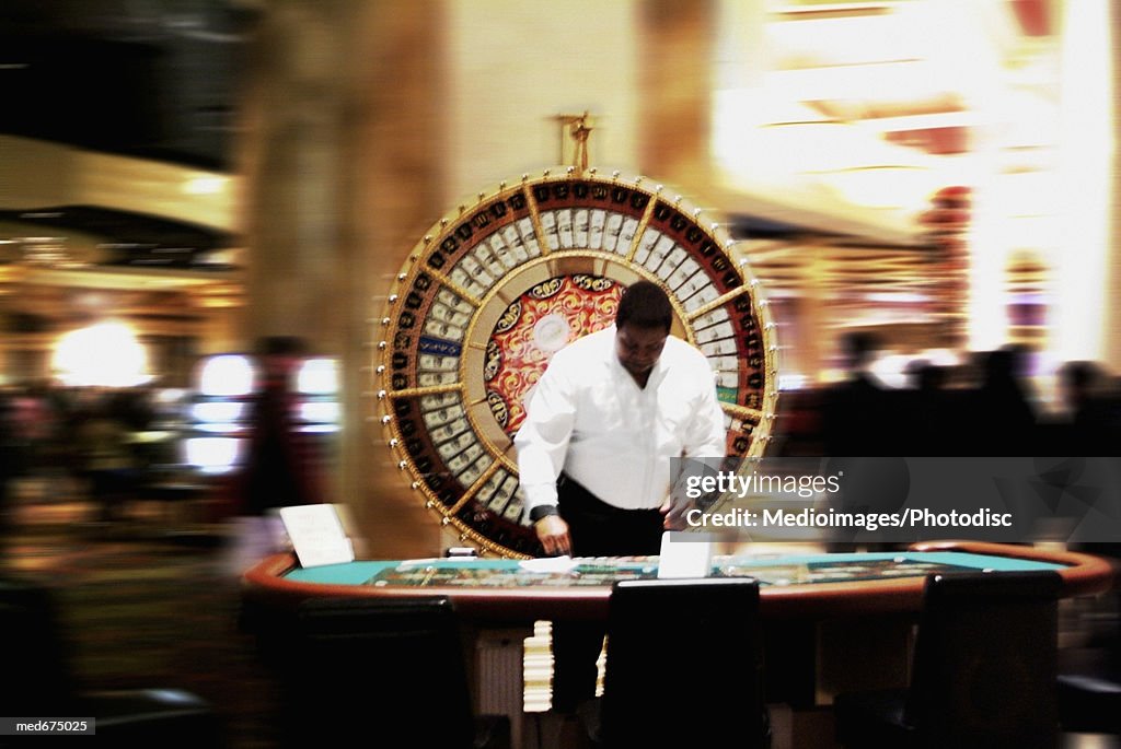 African-American employee in front of wheel of fortune in casino