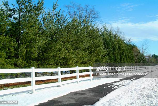 empty road with white fence and snow in winter, part of - altocumulus stock pictures, royalty-free photos & images