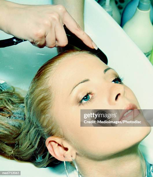 woman having her hair rinsed at a salon, close-up, part of - beauty salon foto e immagini stock