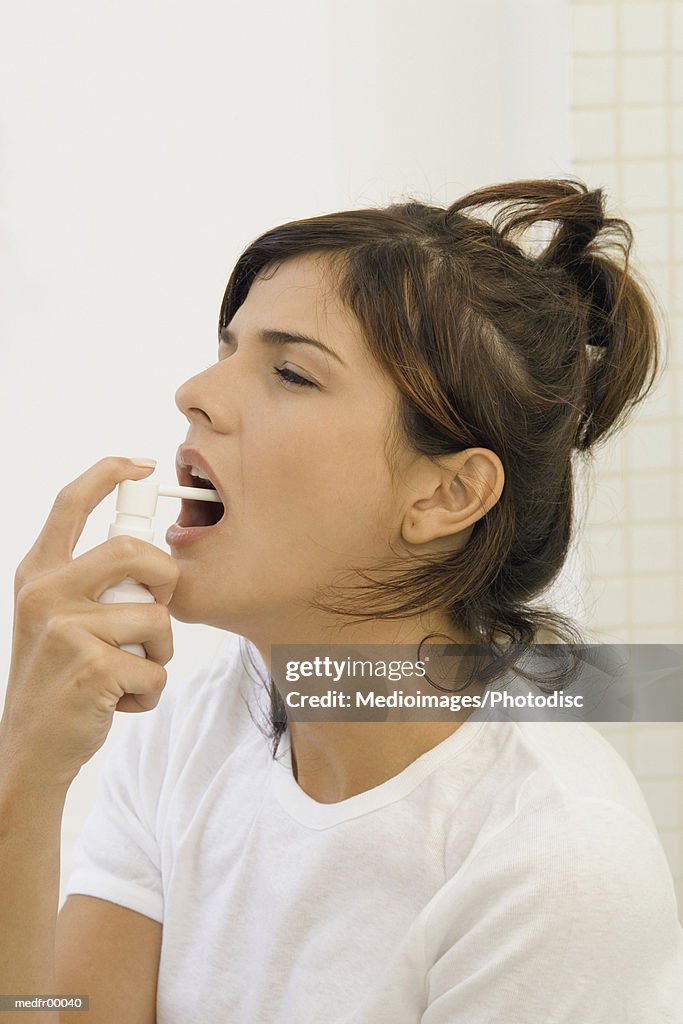 Young woman spraying mouth spray, close-up