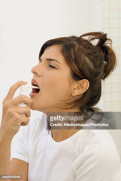 young woman spraying mouth spray, close-up - mouth spray stock pictures, royalty-free photos & images