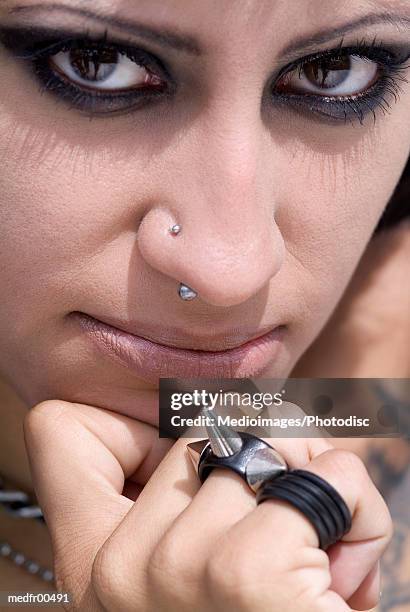 extreme close-up of young woman she has a pierced nose and is holding a studded bracelet - holding nose stock pictures, royalty-free photos & images