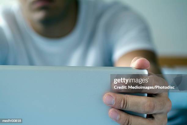 close-up of a man holding a laptop screen - closed laptop stock pictures, royalty-free photos & images