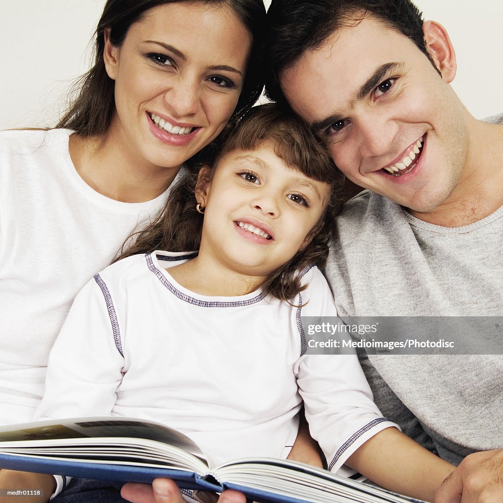 Smiling couple and child with scrapbook, close-up