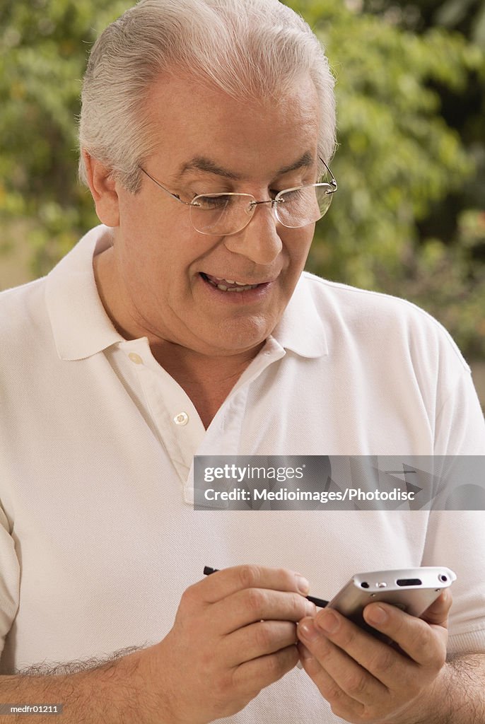 Smiling senior man using palmtop outdoors, close-up