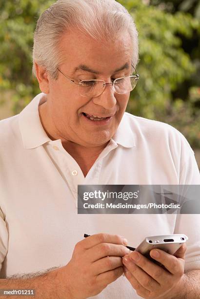 smiling senior man using palmtop outdoors, close-up - silver surfer - fotografias e filmes do acervo