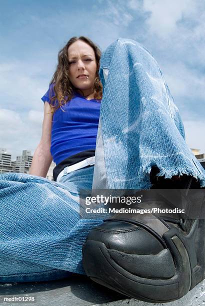 low angle view of a young woman sitting on the ground - finger waves ストックフォトと画像