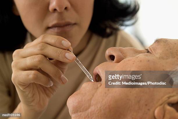 a woman checking temperature of a senior citizen - citizen stock-fotos und bilder