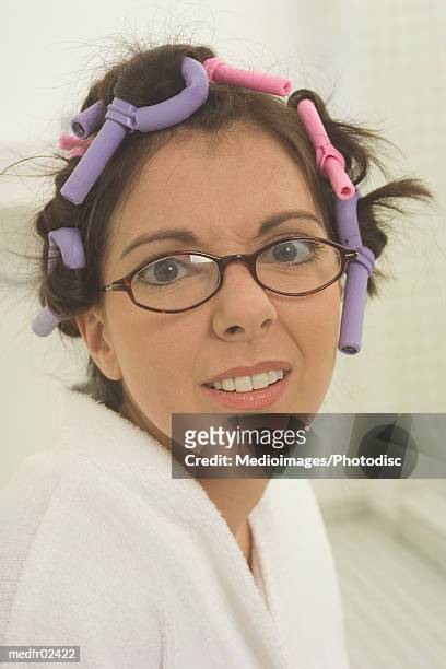 a woman wearing a bath robe with curlers in her hair - hair curlers stockfoto's en -beelden