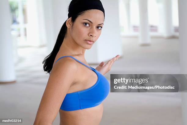 Young Woman in Sports Bra Holding Football with Hand on Hip Stock