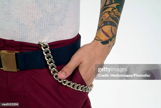 mid section image of man's hand in pocket; man has tattoo and chain on pants, close-up - pocket chain foto e immagini stock