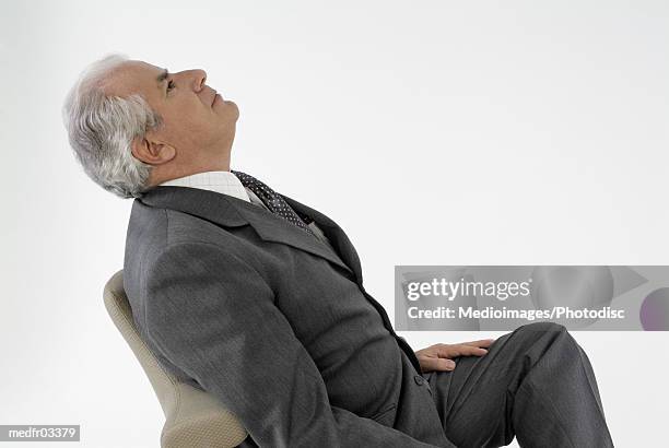 side view of a mature man leaning back on chair looking up - back of chair stock pictures, royalty-free photos & images