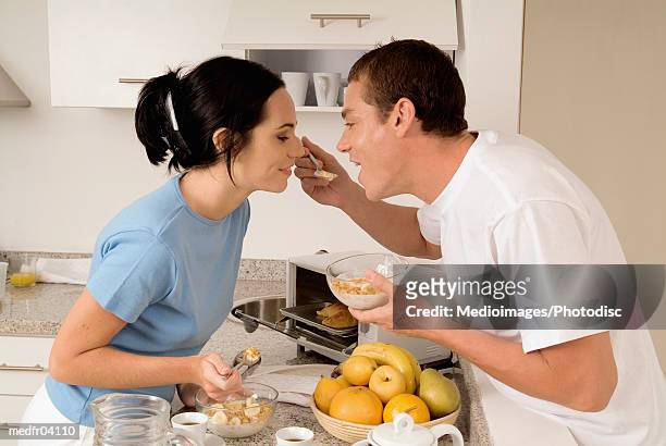 young couple standing in kitchen having breakfast - go bananas stockfoto's en -beelden
