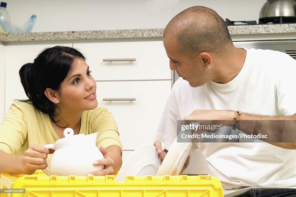Couple unpacking dishes and teapot in kitchen, close-up