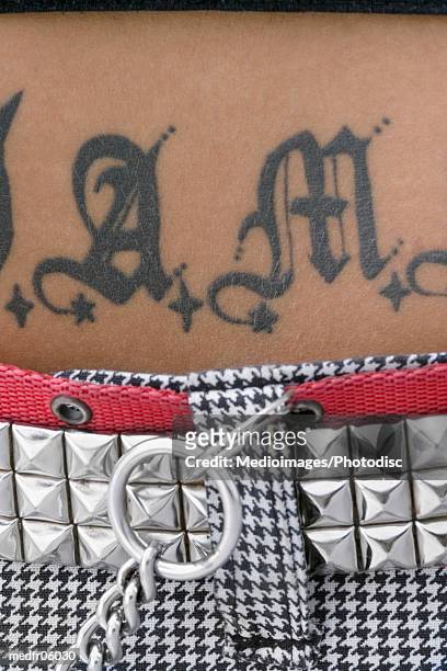 midriff of woman with studded belt and tattoo on stomach, close-up - belt stockfoto's en -beelden