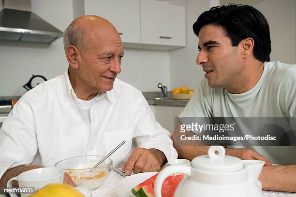 senior man and mid adult man having breakfast in kitchen, close-up - pour spout stock pictures, royalty-free photos & images