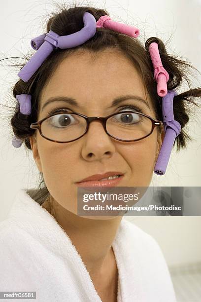 young woman making a face with curlers in her hair - hair curlers stockfoto's en -beelden