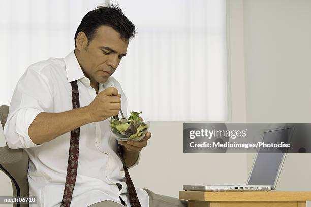 a man eating salad from a bowl - untied stock pictures, royalty-free photos & images