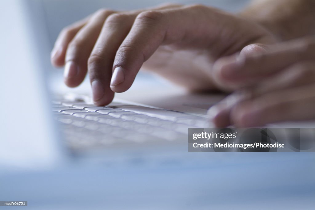 Hands typing on laptop computer, close-up