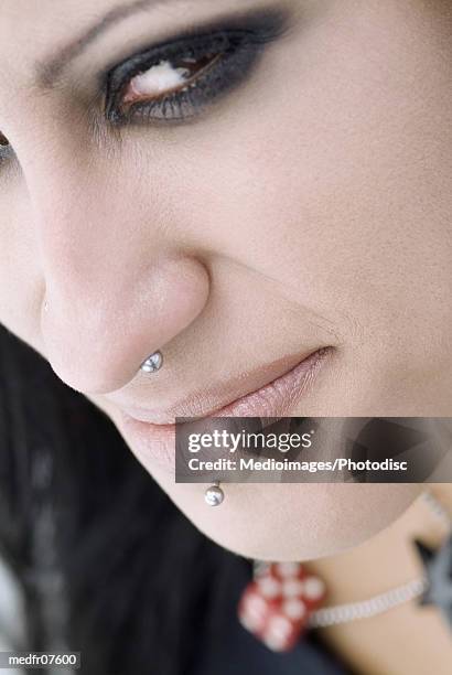 close-up of a young woman with facial piercing looking at camera - mouth smirk stock pictures, royalty-free photos & images