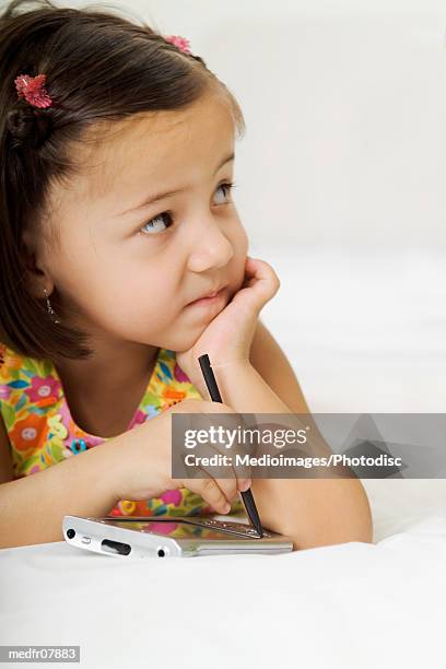 three year old girl with palmtop on bed, close-up - year on year stock pictures, royalty-free photos & images