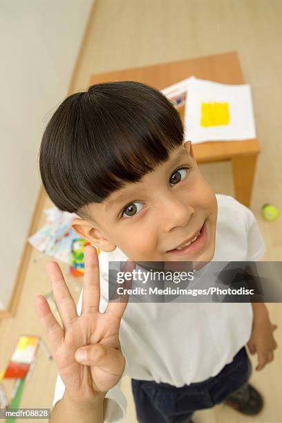 young boy standing and holding up four fingers, close-up - person holding up 4 fingers stock pictures, royalty-free photos & images
