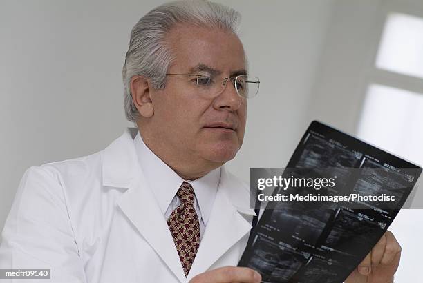 elderly doctor looking at an x-ray film - gifted film ストックフォトと画像