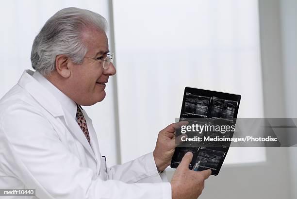 elderly doctor holding an x-ray film - gifted film ストックフォトと画像