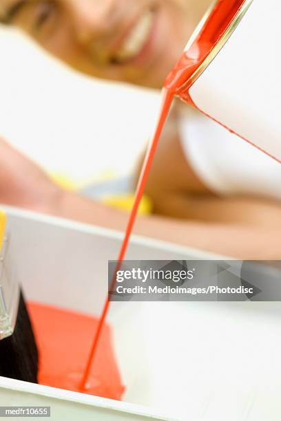 man pouring red paint into roller pan, close-up, selective focus, focus on paint - pan stock-fotos und bilder