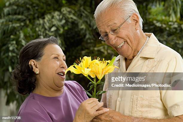 smiling senior man and woman with flowers outdoors, close-up - lili gentle fotografías e imágenes de stock