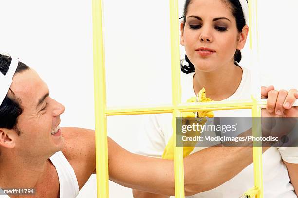 smiling man and woman painting wood frame yellow, close-up - wood frame ストックフォトと画像
