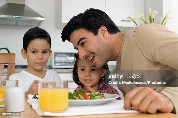 smiling man and two children having lunch or dinner - or stock pictures, royalty-free photos & images