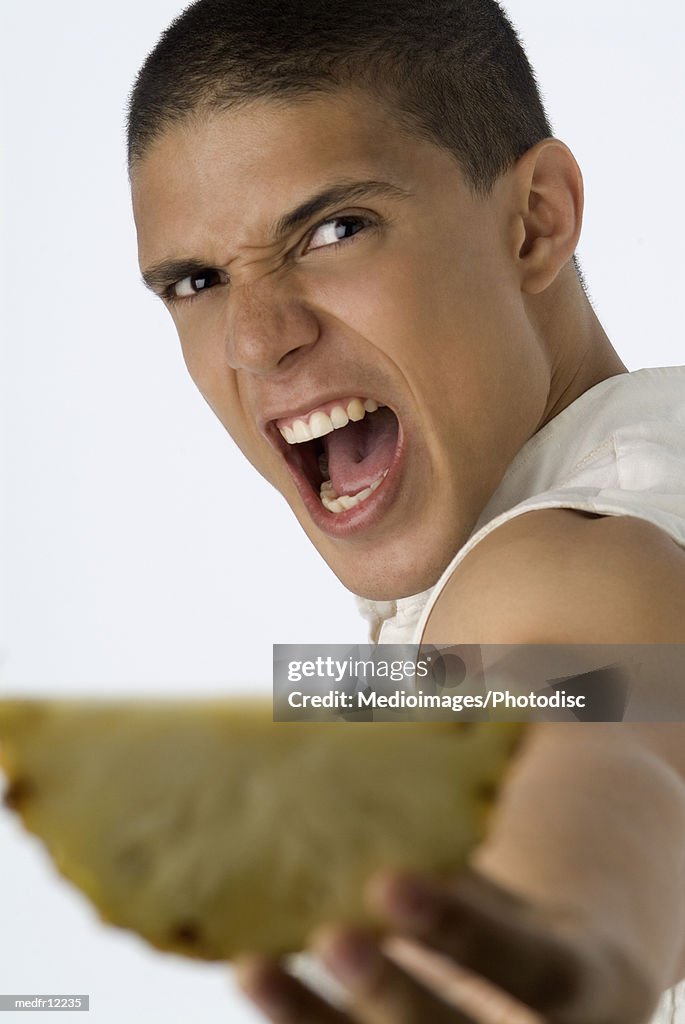 Close-up of a young man holding out slice of fruit