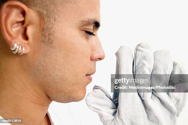 young man with leather gloves praying, close-up - body modification stock-fotos und bilder
