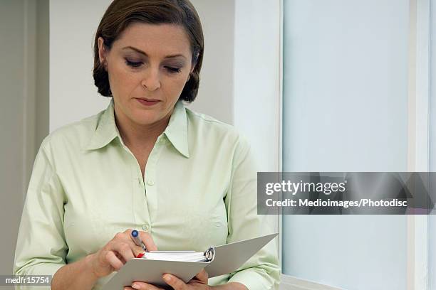 businesswoman in green blouse holding pen and appointment book, close-up - green book stock pictures, royalty-free photos & images