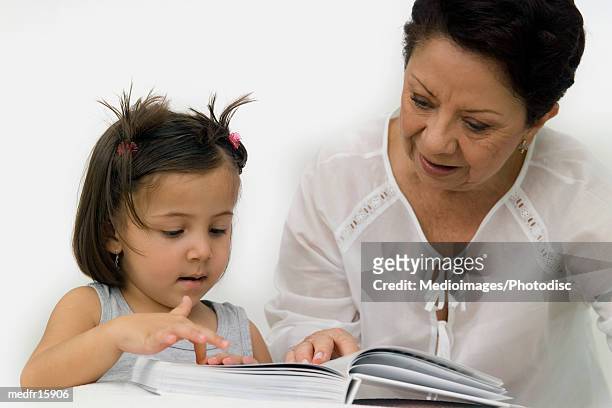 three year old girl reading with senior woman, close-up - federation of new yorks music visionary of the year award luncheon stockfoto's en -beelden