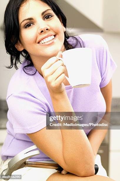 woman in lavender top and white shorts holding hammer and coffee cup, close-up - klauwhamer stockfoto's en -beelden