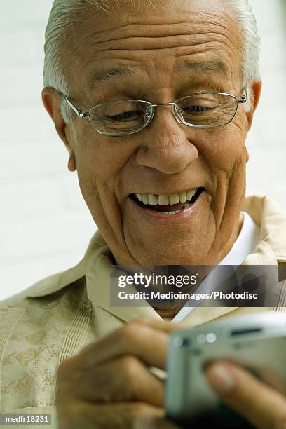 smiling senior man using palmtop, close-up - silver surfer - fotografias e filmes do acervo